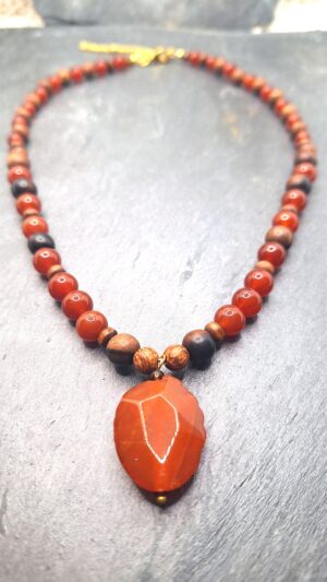 Collier Cornaline et bois - Cabochon facetté. CORNALINE. Elle est une pierre d’enthousiasme et de vitalité. Accroit la motivation, stimule et énergise. Aide à la concentration. Facilite la compréhension entre les personnes. Stimule la créativité et la concentration. Apaise la colère. Apporte enthousiasme, courage et assurance. Chasse les émotions et pensées négatives ainsi que les cauchemars. Apaise les sentiments de rancune. Protège les lieux et les personnes. Agit sur la fertilité des femmes.